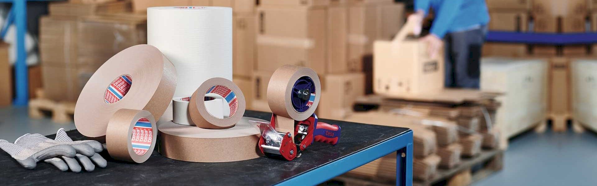 Automated packaging line with machines applying custom adhesive tapes to cartons