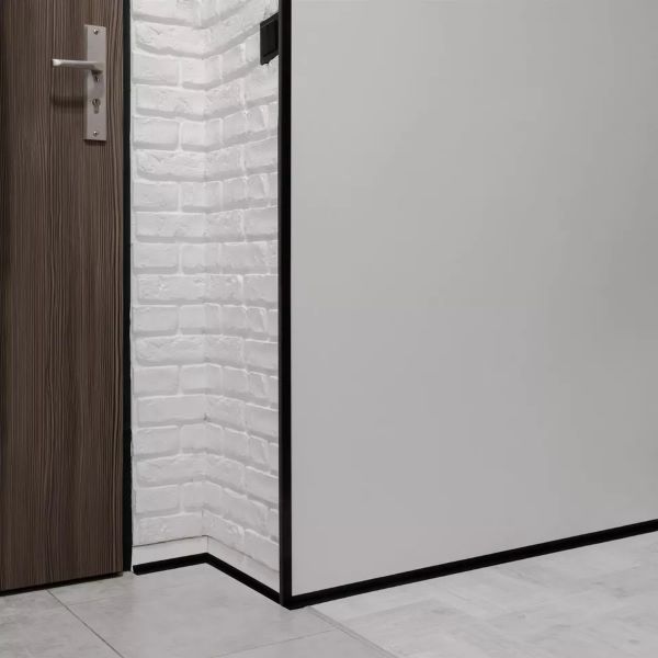 Close up of black PVC corner trim profile, 1m long, protecting a wall corner from mechanical damage with a neat decorative finish