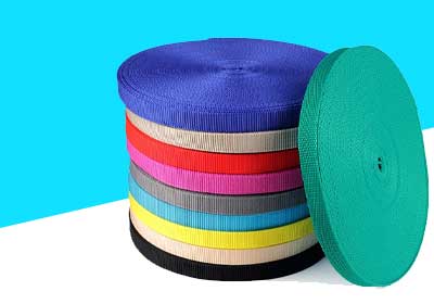 Polypropylene webbing rolls in various colours and widths arranged on a workbench